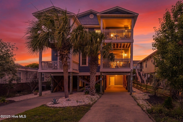 coastal inspired home featuring a carport, a balcony, and covered porch