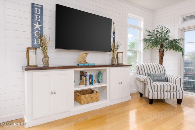 living area featuring ornamental molding and light hardwood / wood-style floors