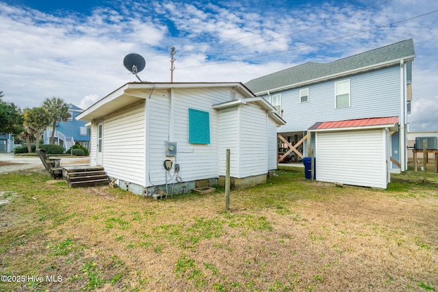 rear view of property with central AC and a lawn