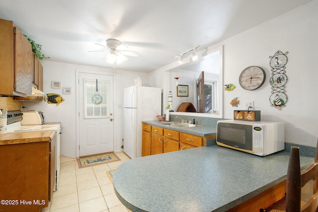 kitchen featuring ceiling fan, sink, light tile patterned flooring, and white appliances