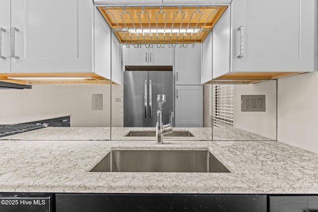 kitchen featuring white cabinetry, sink, and stainless steel fridge