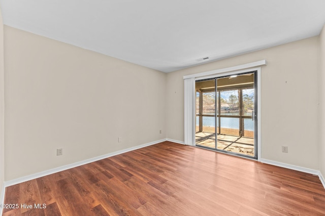 unfurnished room featuring hardwood / wood-style flooring and a water view