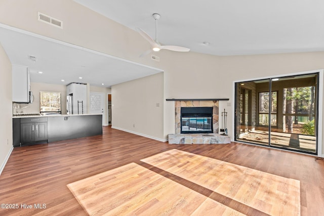 unfurnished living room featuring light hardwood / wood-style flooring, sink, vaulted ceiling, and ceiling fan