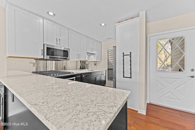 kitchen with kitchen peninsula, white cabinets, and range