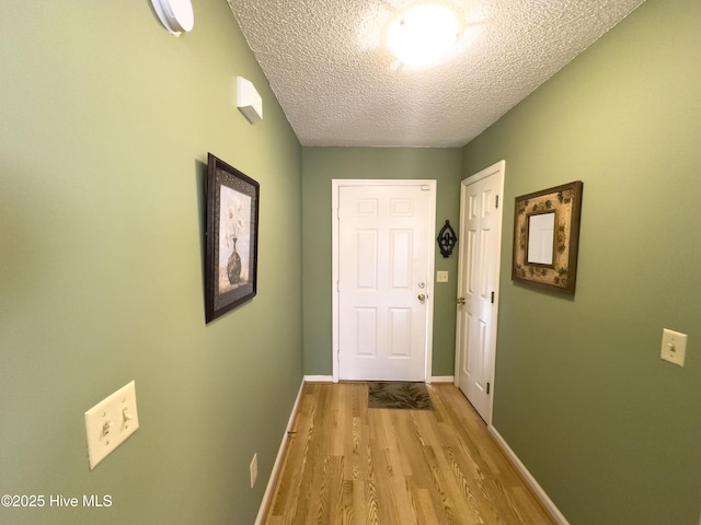 hall with light hardwood / wood-style flooring and a textured ceiling