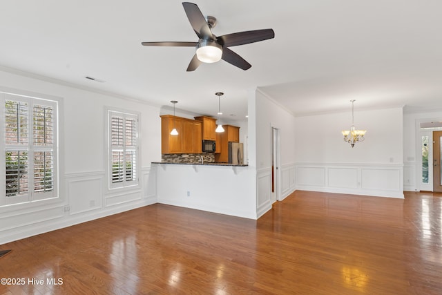 unfurnished living room featuring dark hardwood / wood-style flooring, crown molding, and ceiling fan with notable chandelier