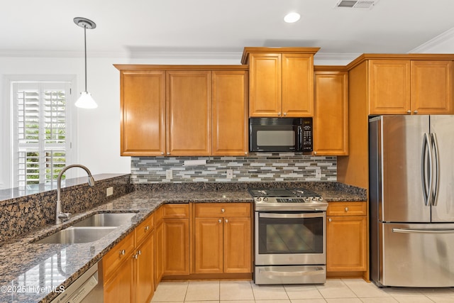 kitchen with sink, ornamental molding, appliances with stainless steel finishes, pendant lighting, and dark stone counters