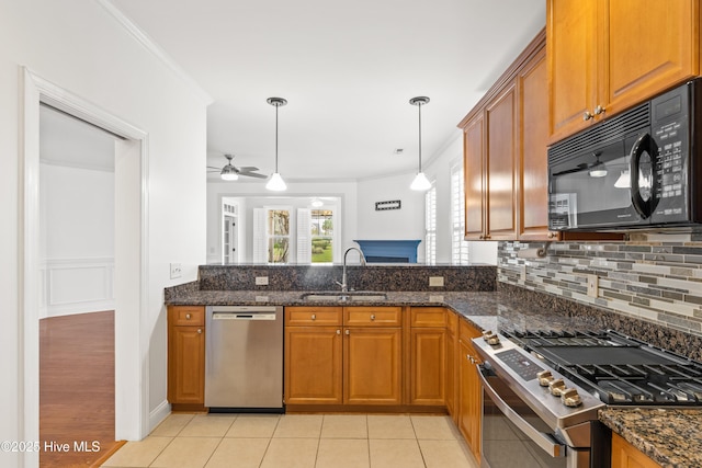 kitchen with pendant lighting, sink, stainless steel appliances, and dark stone countertops