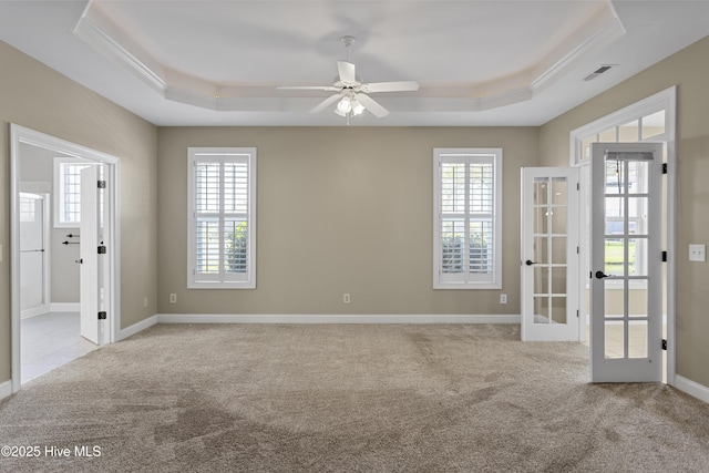 carpeted spare room with a raised ceiling, ceiling fan, and french doors