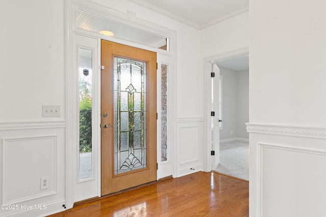 foyer with ornamental molding and light hardwood / wood-style floors