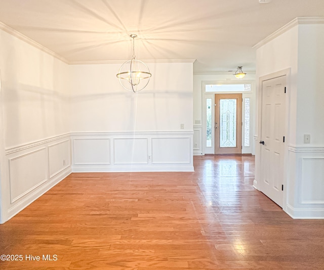 entryway featuring crown molding, an inviting chandelier, and hardwood / wood-style floors