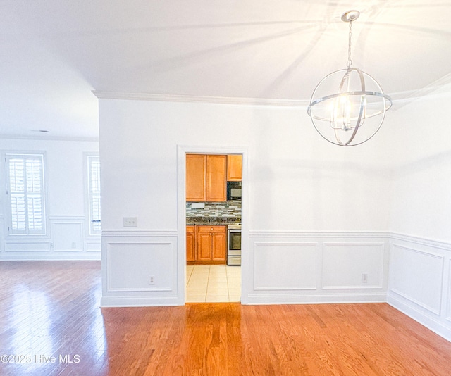 interior space featuring crown molding, a notable chandelier, and light hardwood / wood-style flooring