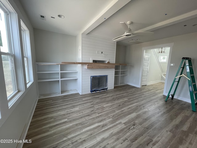 unfurnished living room with hardwood / wood-style flooring, ceiling fan, and a healthy amount of sunlight