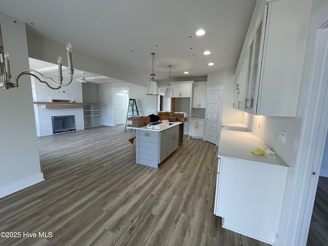 kitchen with recessed lighting, a large fireplace, wood finished floors, white cabinetry, and open floor plan