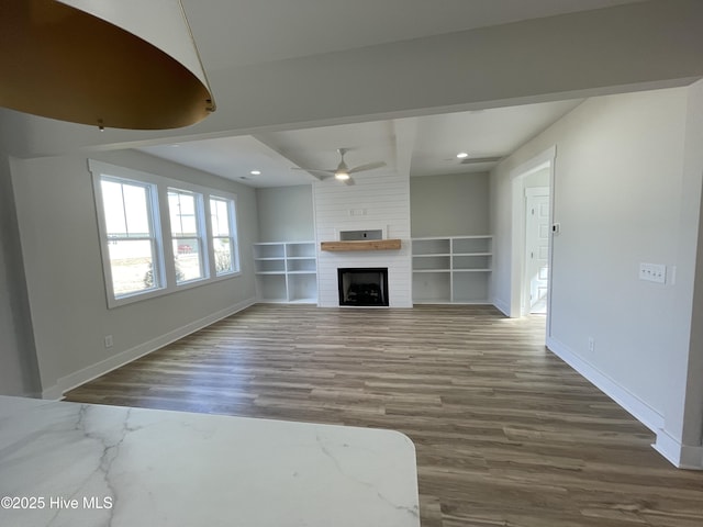 unfurnished living room with a large fireplace, baseboards, a ceiling fan, wood finished floors, and recessed lighting