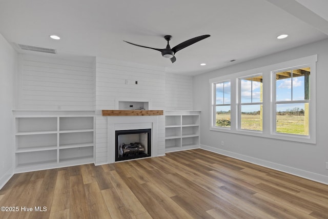 unfurnished living room featuring hardwood / wood-style floors, a large fireplace, and ceiling fan