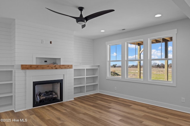 unfurnished living room featuring hardwood / wood-style flooring, ceiling fan, and a fireplace