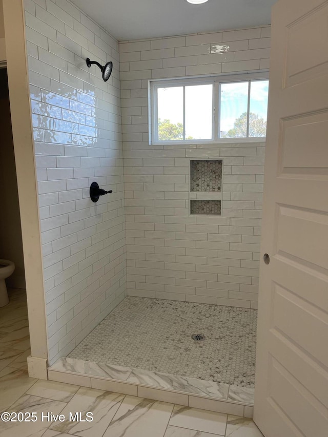 bathroom featuring a stall shower, marble finish floor, and toilet