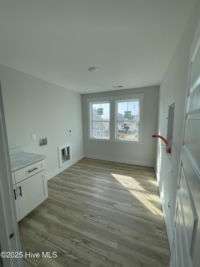 clothes washing area featuring visible vents, wood finished floors, cabinet space, and baseboards