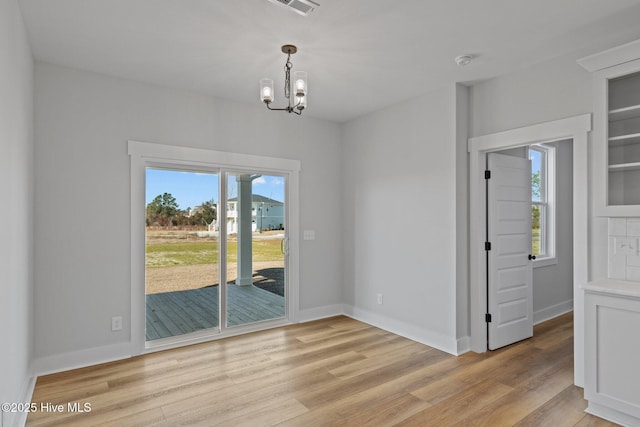 unfurnished dining area with a chandelier, light wood finished floors, visible vents, and baseboards