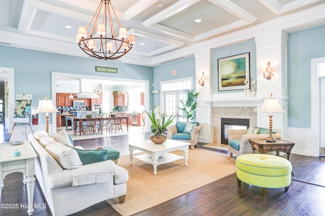 living room with coffered ceiling, wood-type flooring, ornamental molding, beamed ceiling, and a chandelier