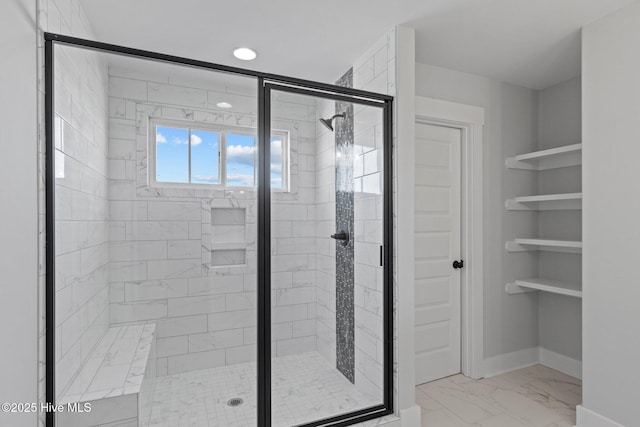 bathroom featuring marble finish floor, baseboards, and a stall shower