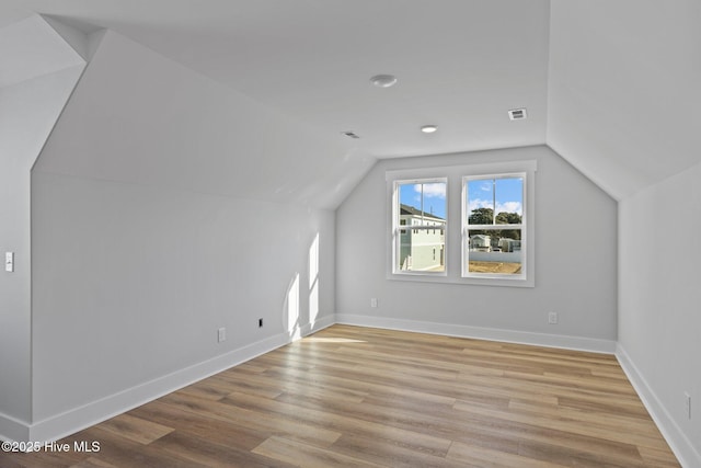 bonus room with vaulted ceiling, baseboards, visible vents, and light wood-style floors