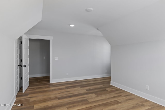 additional living space featuring vaulted ceiling, baseboards, and wood finished floors