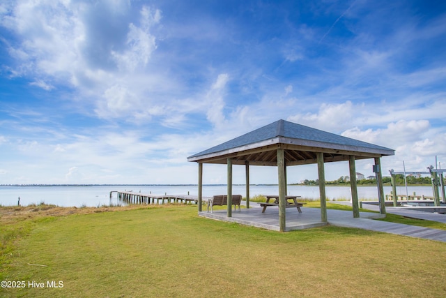 view of dock with a gazebo, a water view, and a yard