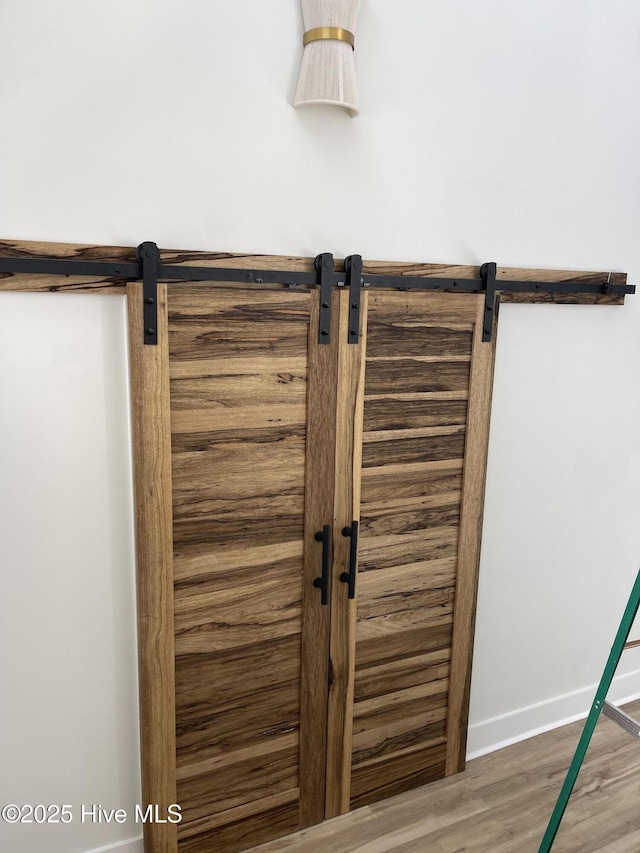 room details featuring wood finished floors, baseboards, and a barn door