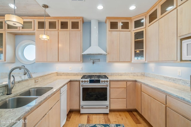 kitchen with gas range, sink, light brown cabinetry, and wall chimney exhaust hood