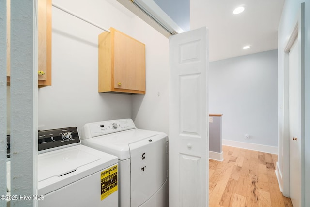 washroom featuring cabinets, separate washer and dryer, and light hardwood / wood-style flooring