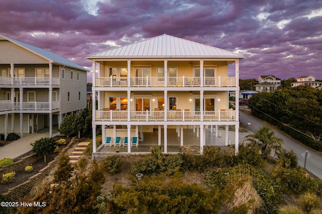 back house at dusk featuring a balcony and a patio area