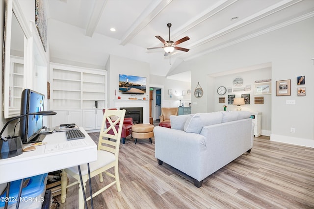 living room with light wood-type flooring, a ceiling fan, beamed ceiling, and a glass covered fireplace