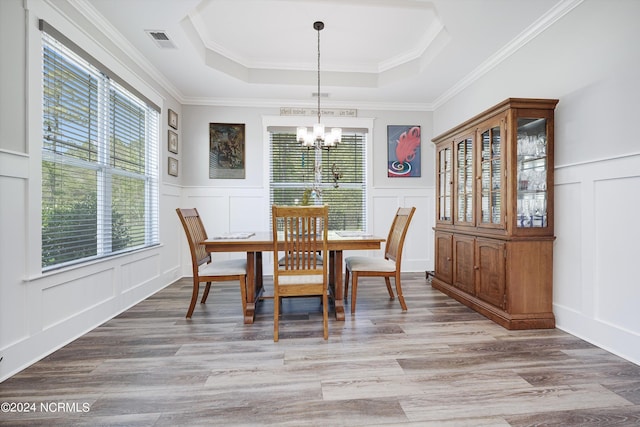 dining space with a wealth of natural light, a raised ceiling, visible vents, and a decorative wall