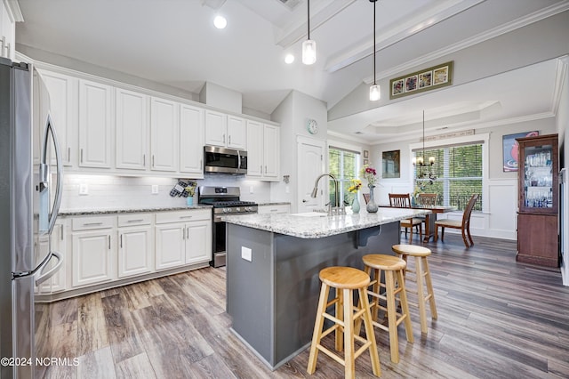 kitchen featuring a breakfast bar area, appliances with stainless steel finishes, white cabinetry, a sink, and wood finished floors