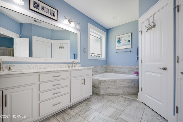 bathroom with double vanity, visible vents, a sink, and a bath