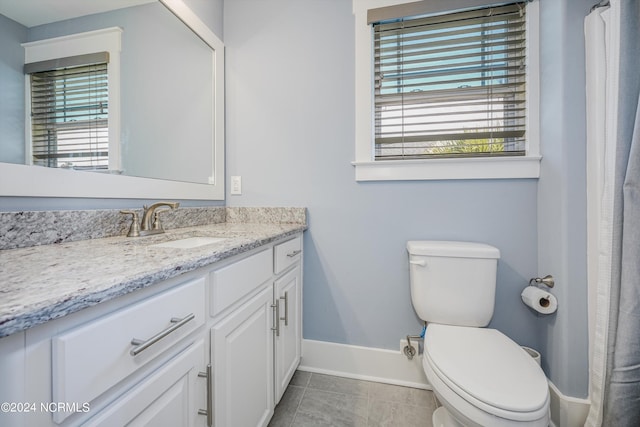 bathroom with plenty of natural light, vanity, toilet, and baseboards