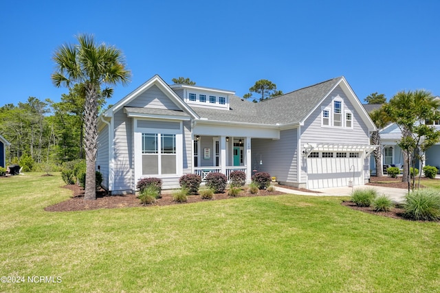 view of front of home featuring an attached garage, driveway, covered porch, and a front yard