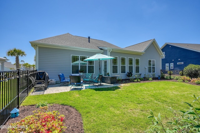 rear view of house featuring a patio area, a lawn, a fenced backyard, and roof with shingles