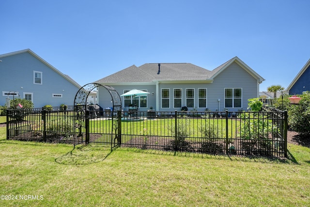 rear view of house featuring a lawn and fence