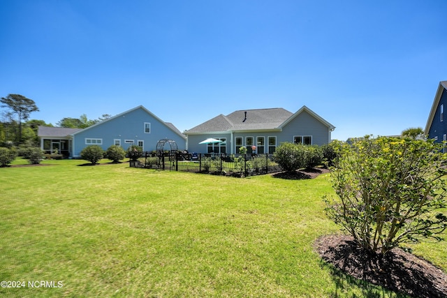 rear view of property featuring a lawn and fence