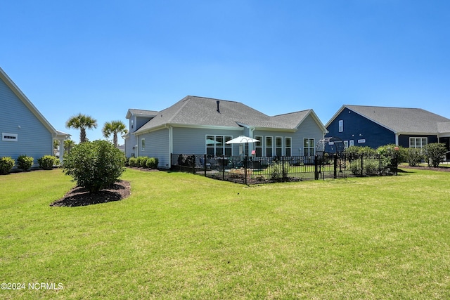 rear view of property with fence and a yard