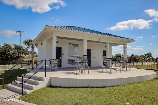 exterior space with stucco siding, a lawn, a standing seam roof, fence, and metal roof