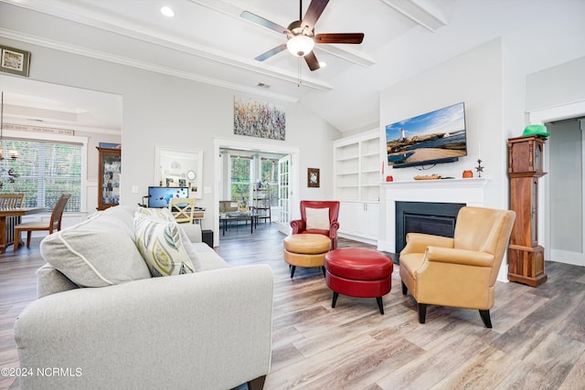 living room featuring vaulted ceiling with beams, wood finished floors, a ceiling fan, a glass covered fireplace, and crown molding