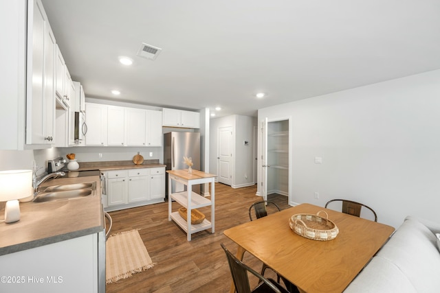 kitchen with sink, dark wood-type flooring, white cabinets, and appliances with stainless steel finishes