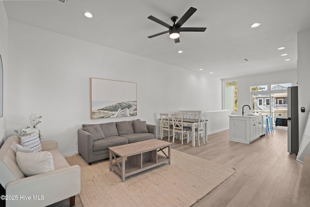 living room featuring sink, light hardwood / wood-style flooring, and ceiling fan