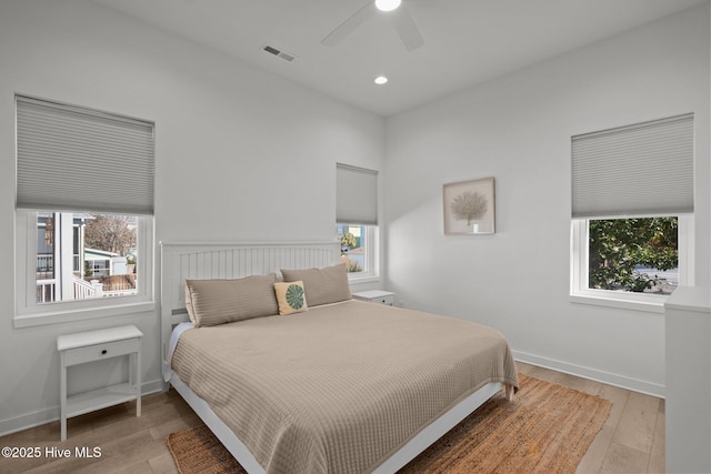 bedroom featuring ceiling fan, wood-type flooring, and multiple windows