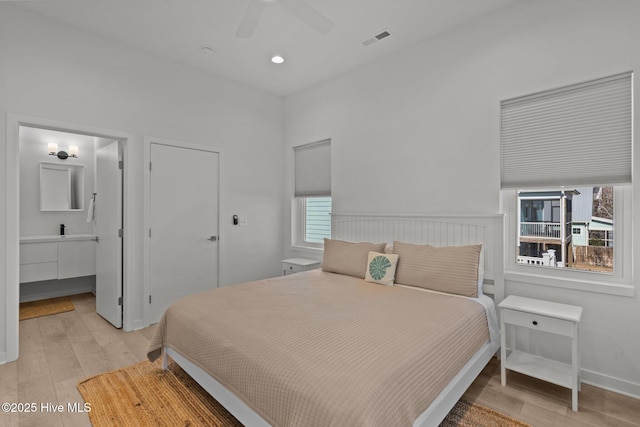 bedroom with connected bathroom, ceiling fan, and light hardwood / wood-style flooring