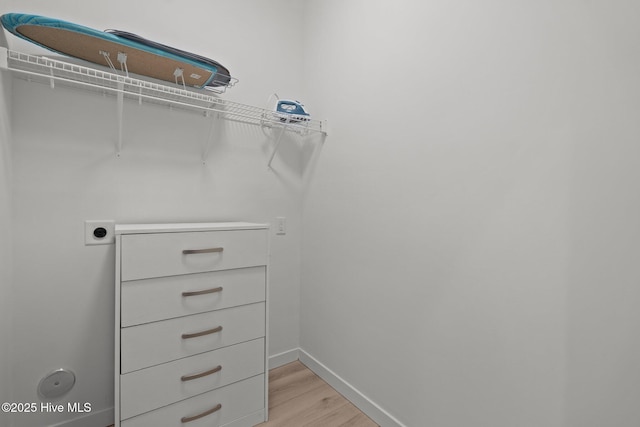 walk in closet with light hardwood / wood-style floors